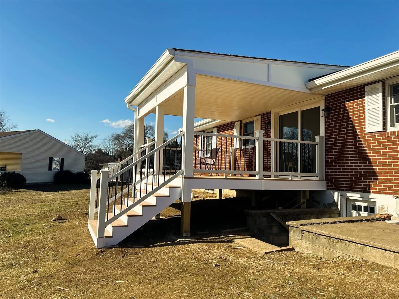 Covered porch with 13x16 composite deck and Trex railing built by Ridgeline Carpentry