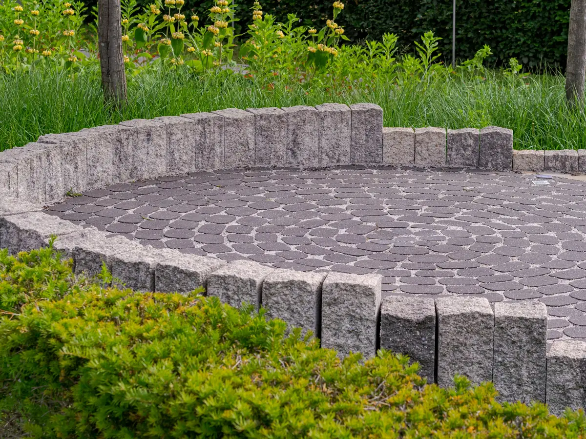 Circular paver patio edged with upright stone and low shrubs