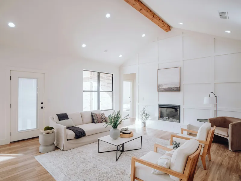 A bright living room with white walls, paneled accent wall and vaulted ceiling