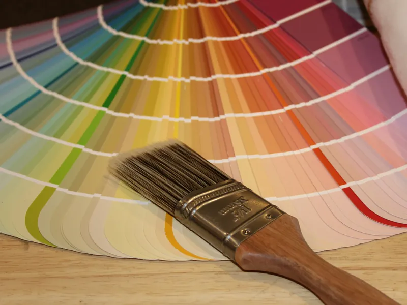 A paint brush resting on an open fan deck of color swatches