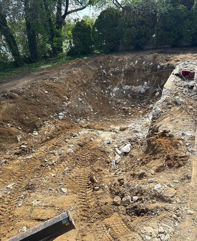 Excavator with breaker working through rock and rebar