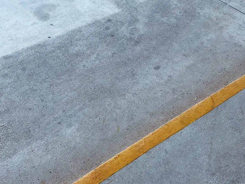 Concrete slab with a lighter cleaned patch beside darker stained concrete