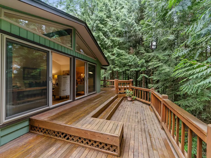 Wood deck with railings and built-in steps along the back of a house