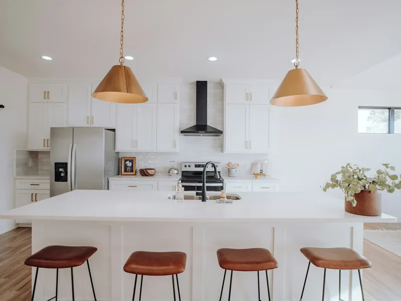 Two brass pendant lights hanging over a white kitchen island