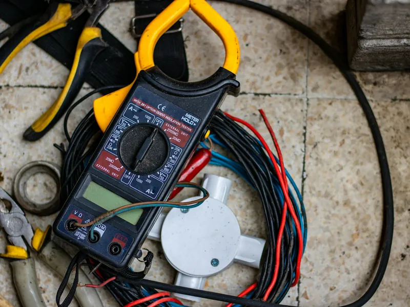 A clamp meter lying on a coil of wire next to pliers