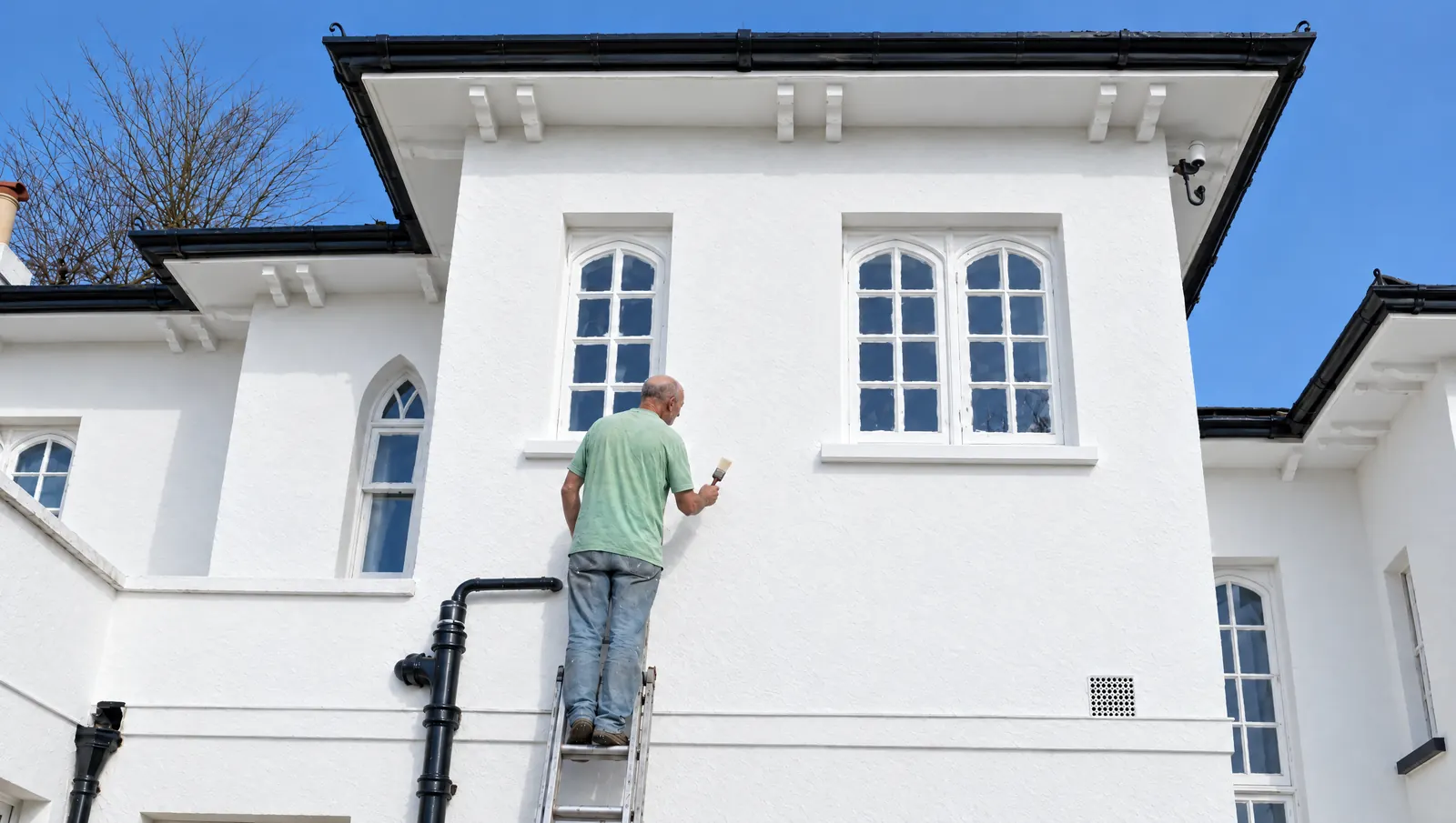 The same house freshly painted, clean white walls under a blue sky